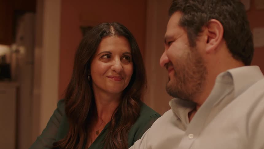A man and woman smile and nod