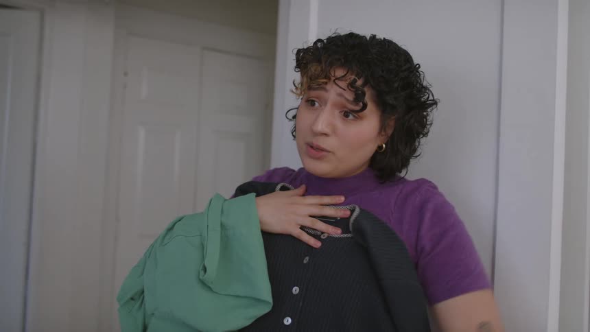 Woman trying on some clothes without getting dressed and not really liking them