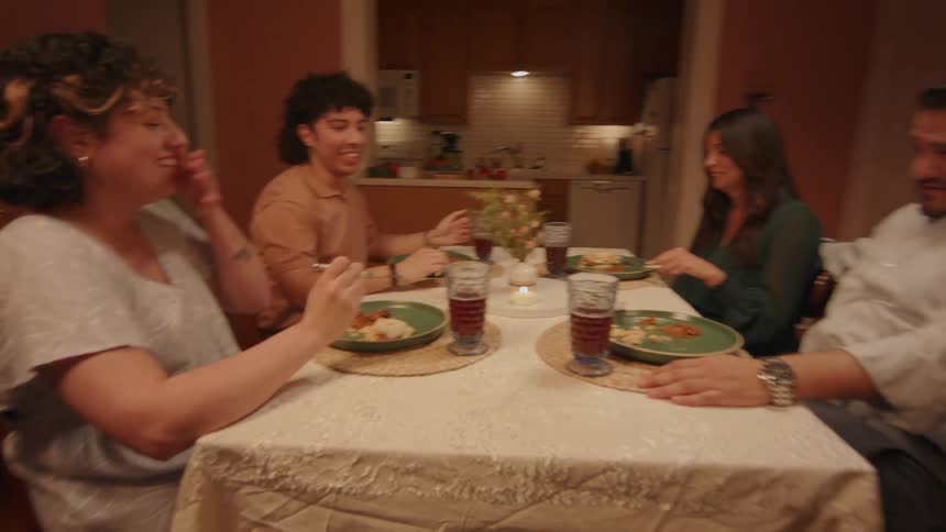 A group of friends laugh while sharing food and drink