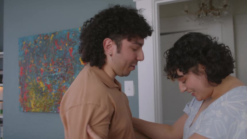 Man stood up from the bed to hug and kiss his wife while they both smiles