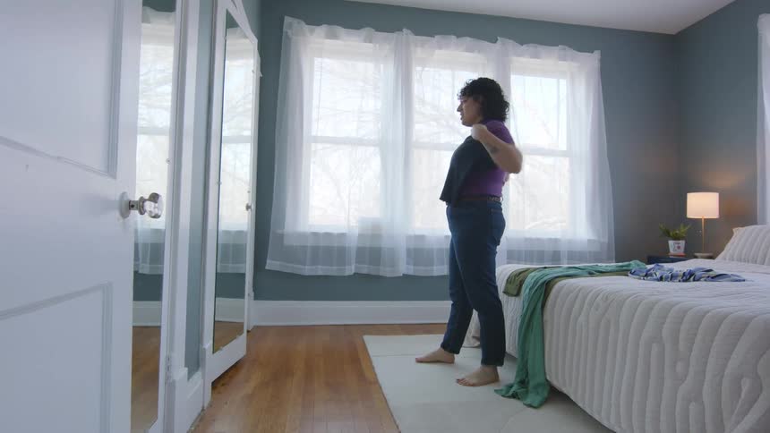 Woman tries clothes in front of the mirror in the bedroom