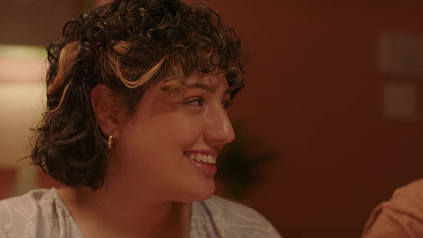A woman smiling in a room talking to people