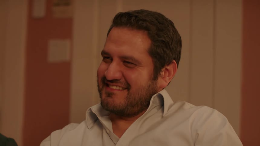 A man sitting in a living room nods smiles speaks and listens