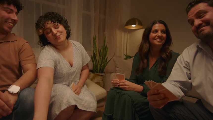 Four friends play cards in a living room