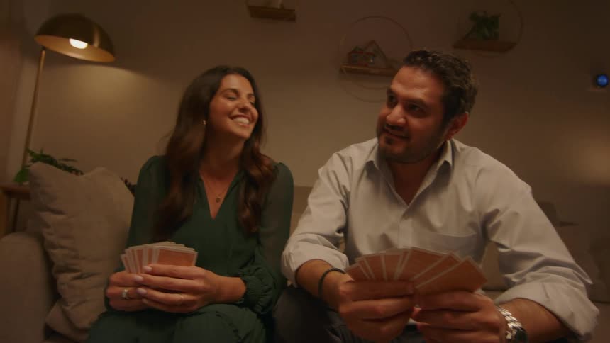 Two couples having a fun game of cards in the living room