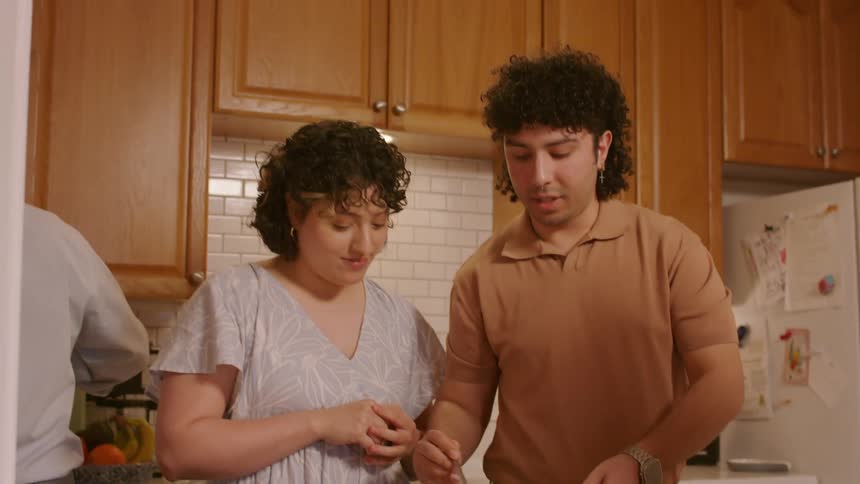 A young couple prepare food together in the kitchen and laugh