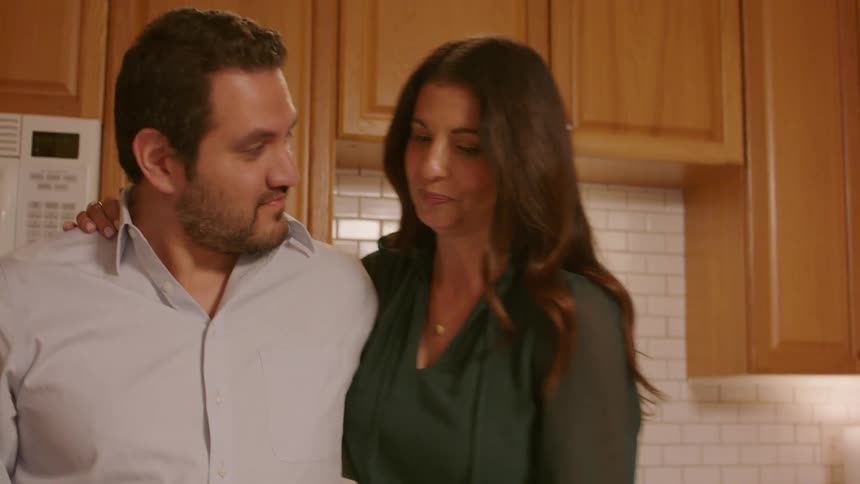A man cooks food and gives a taste to a woman