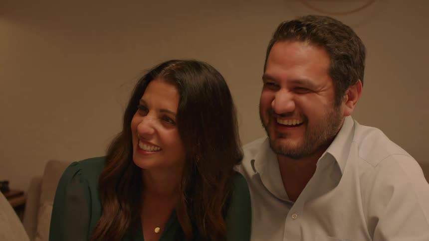 A man and woman talk and laugh with others