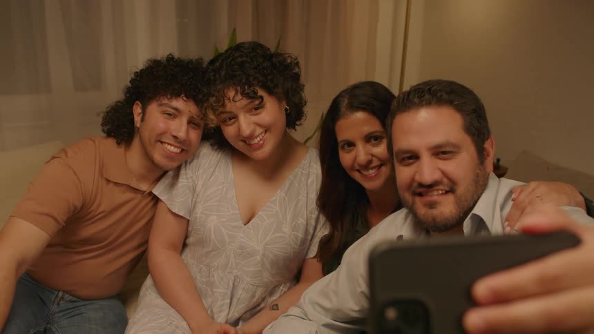 Men and women take picture with a smartphone while seated indoor at night