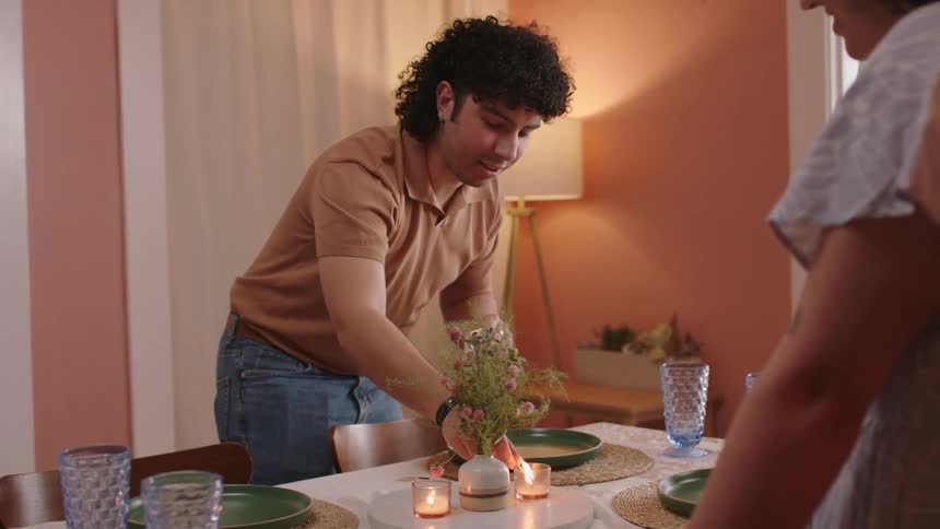 A man lighting a candle at the dinner table