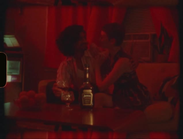 Couple sitting on a couch under a red light have a romantic date caught on vintage film