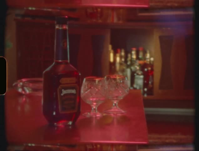 A bottle of alcoholic liquid and two glass glasses on a table