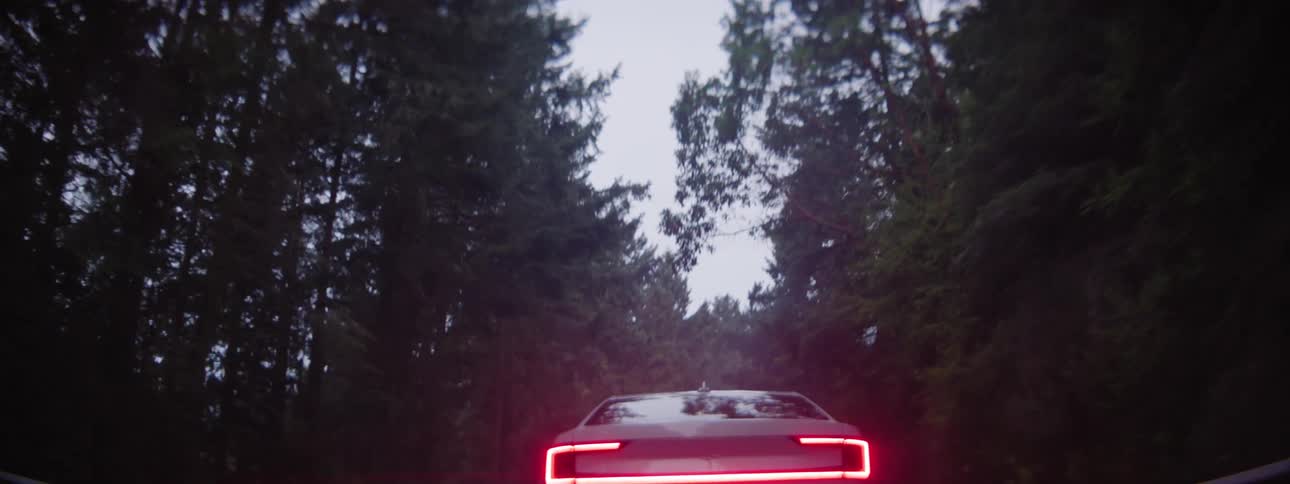 Rear view of a Polestar EV car on one lane road at dawn