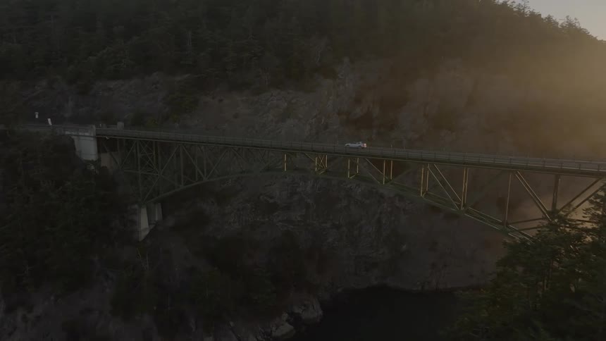 Aerial view of a car driving on a bridge over a gorge at morning
