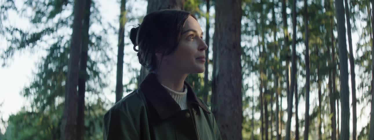 A woman in the forest watching the sunrise