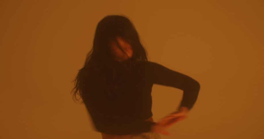 A woman dances and smiles in a dimly lit room