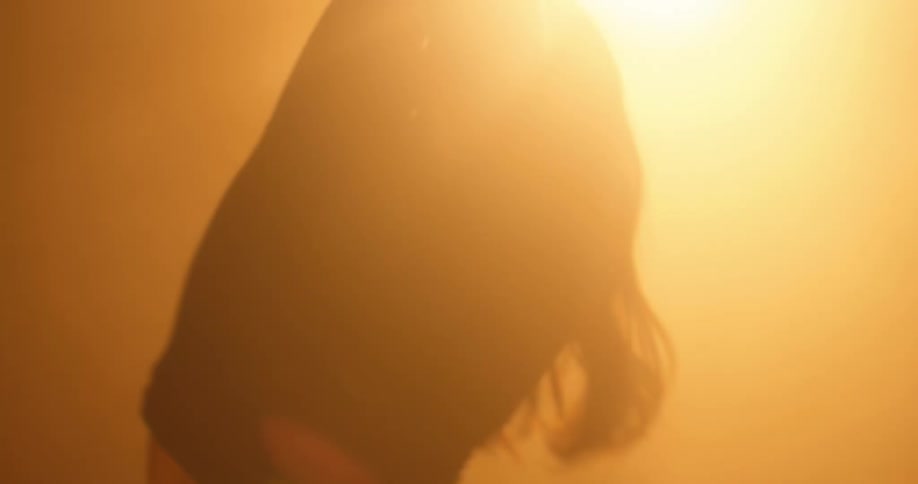 A woman is dancing in front of the sun