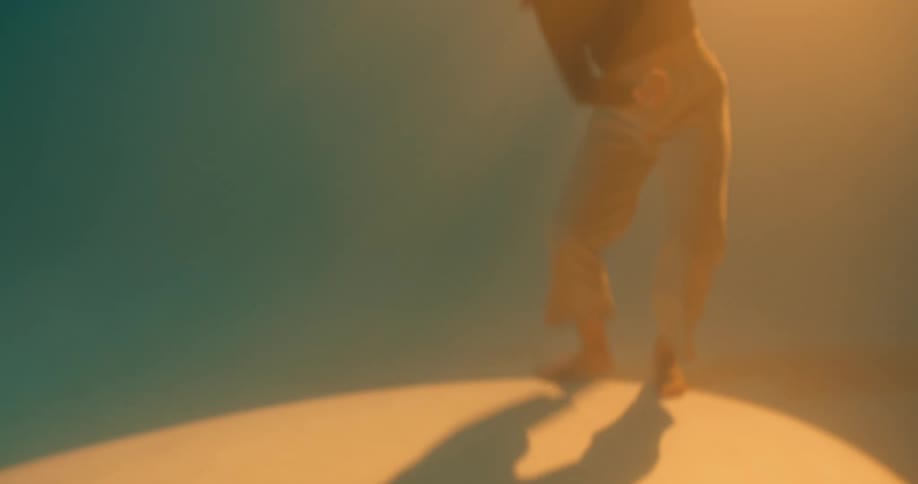 A young woman performs a modern dance under a bright spotlight