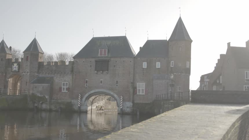 A large castle surrounded by water with a bridge leading to its entrance