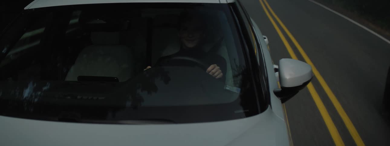 A white car driving on a road through the forest