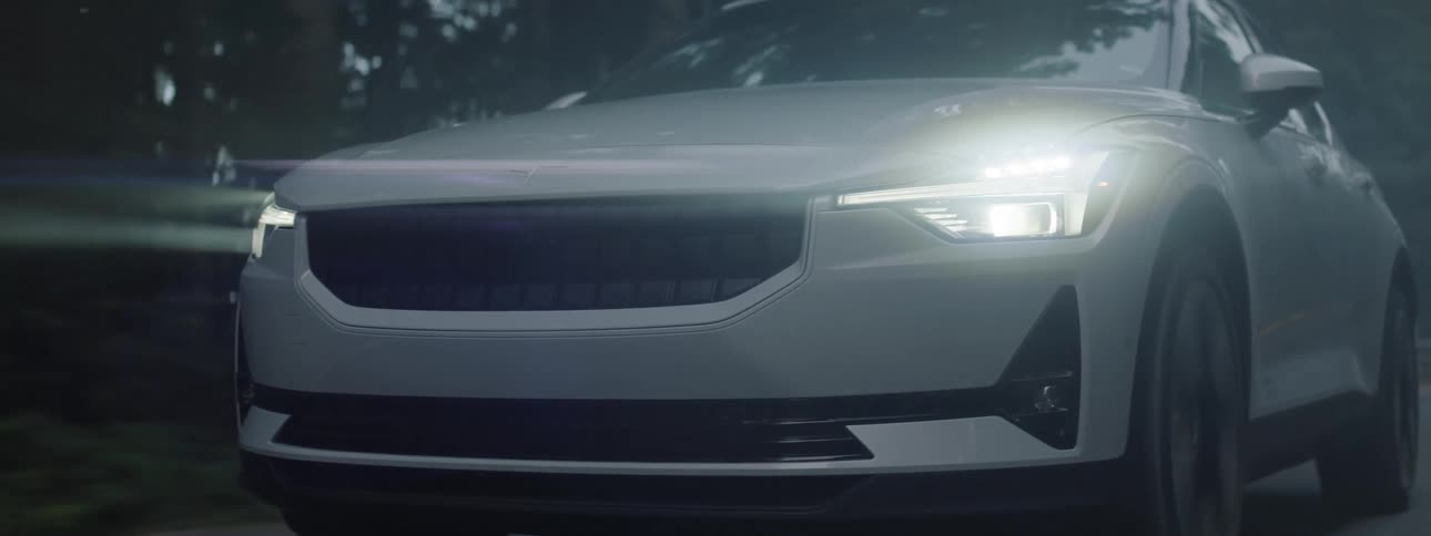 A silver car driving on a foggy road through a forested area