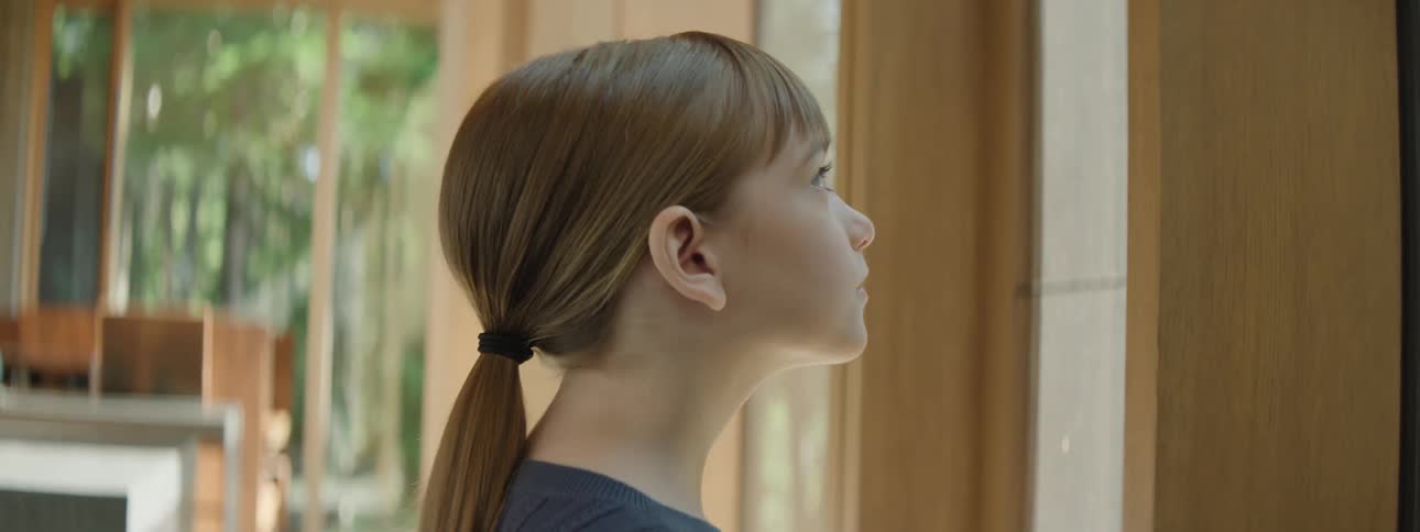 A young girl admiring the landscape from the window of her modern house