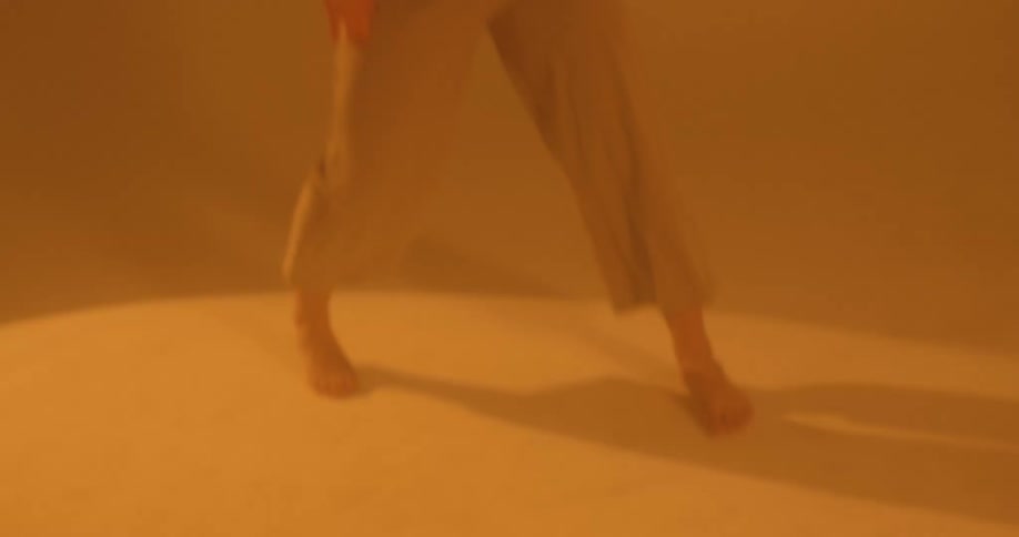 Female dancing barefooted in a yellow room