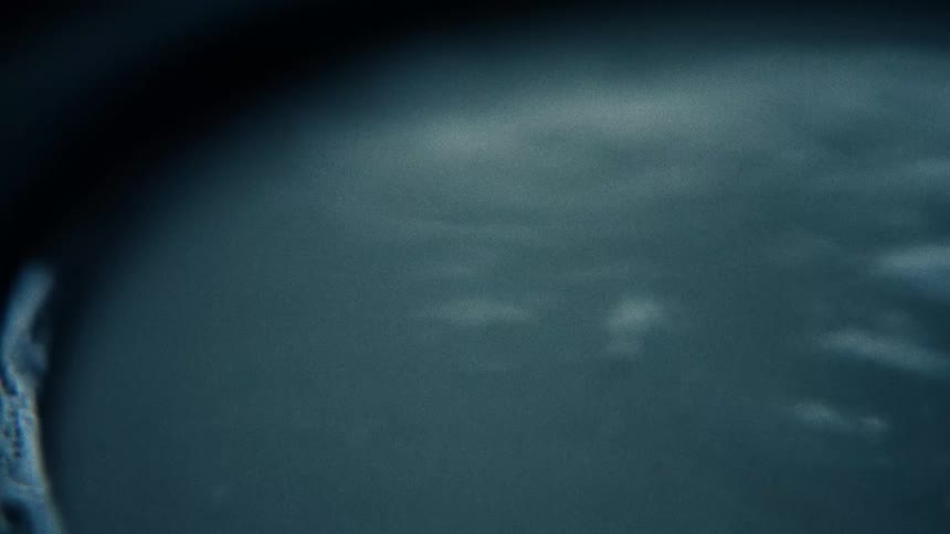 A gray liquid in a container is vibrated which causes ripples across its surface