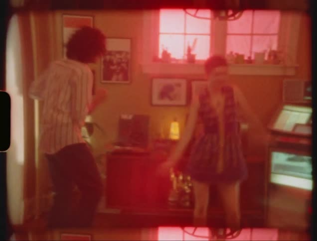 Vintage footage of a young couple dancing near a jukebox