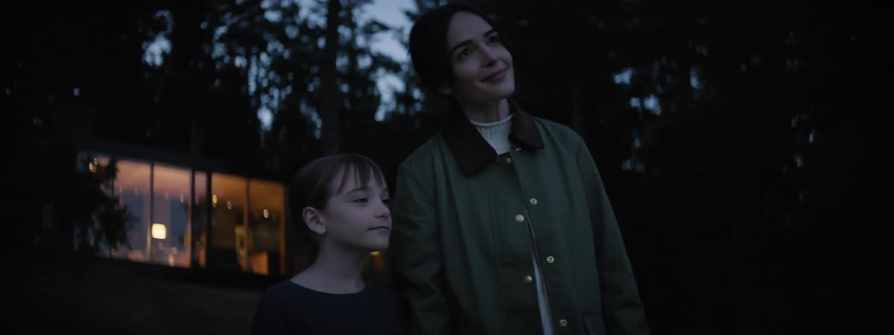 Woman and daughter smiles while standing outdoor at sunset