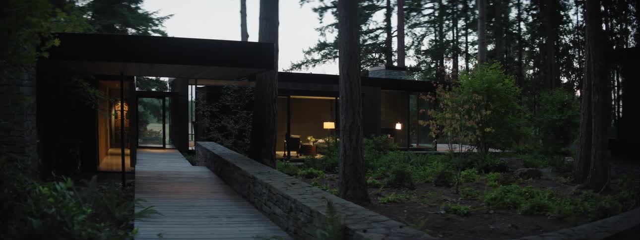 A beautiful modern house in the forest with large glass walls in the evening