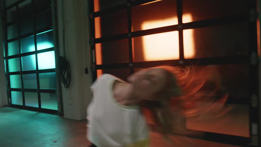 A woman dancing in front of colorful backlit panels