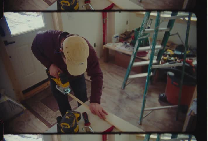 A man measuring some wood to cut in a room