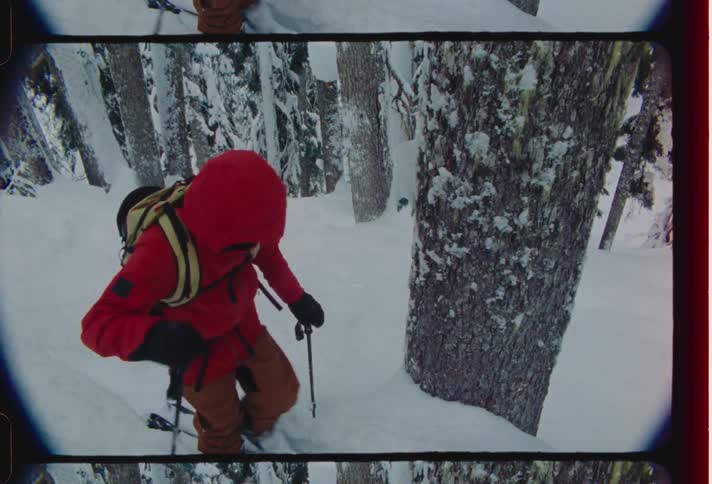 Person climbing a snowcovered mountain amidst trees