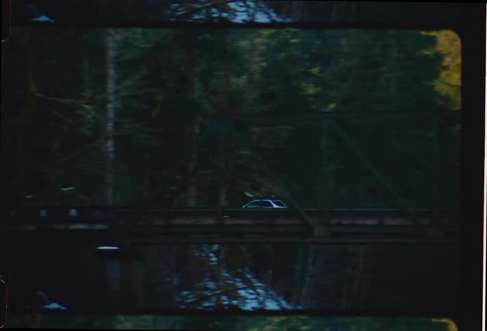 Sedan car crossing a bridge through the forest
