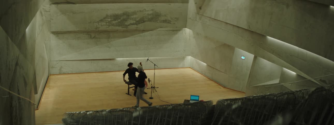Man playing music in a theater with a colleague at his side leaving