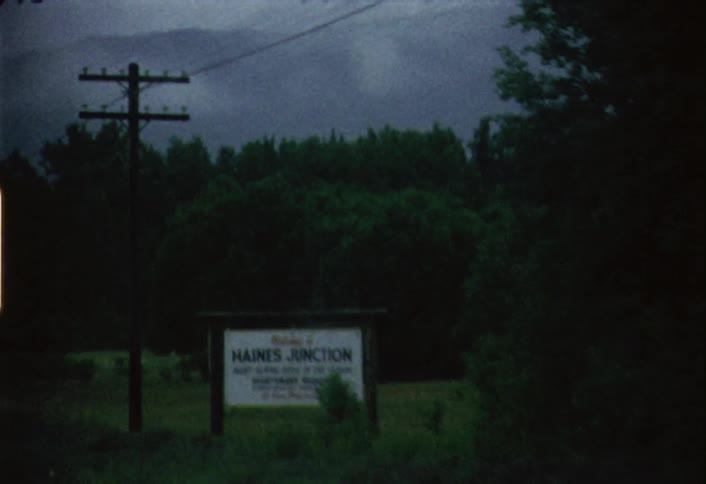 A white sign is on the side of the road