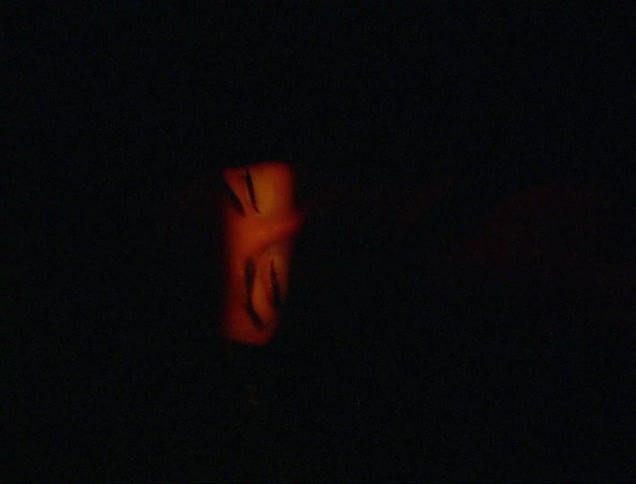 A woman blinks as she lays on her back in the darkness
