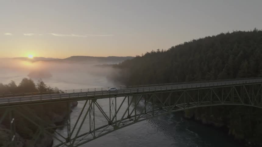 Sedan vehicles crossing a bridge connecting mountains over the sea