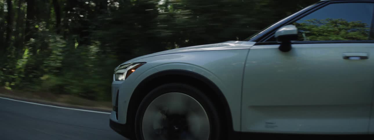 Polestar electric vehicle traveling along a beautiful smokey road in the middle of a forest