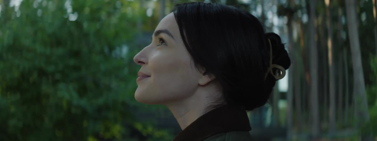 Face of a woman looking up in a forest at morning