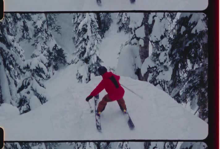 During winter skier skis up slope overlooking conifers then takes jump turning midair
