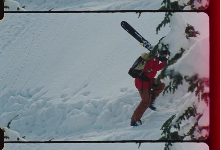 Person with snowboard equipment climbing a mountain covered in snow