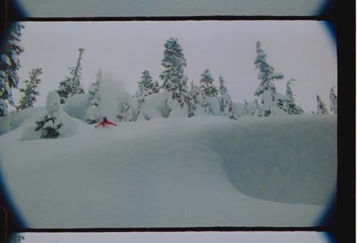 Skier takes jump while skiing down snowy mountain slope