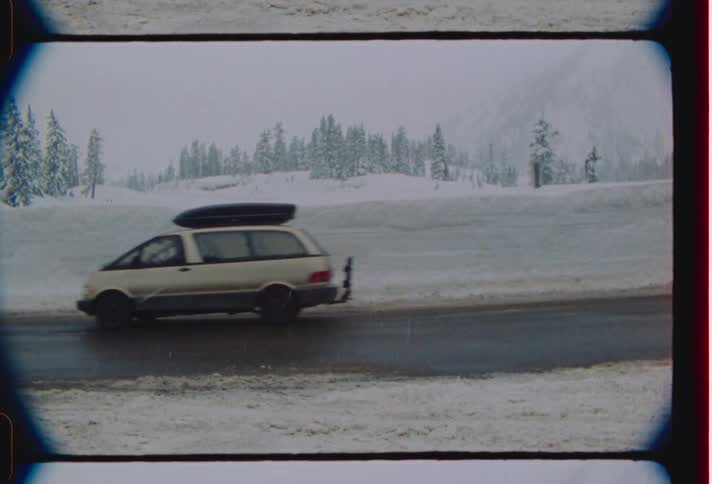 White car driving on road near snowy field