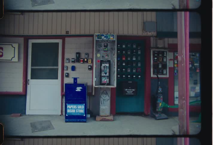 A small town storefront with vending machines and payphones