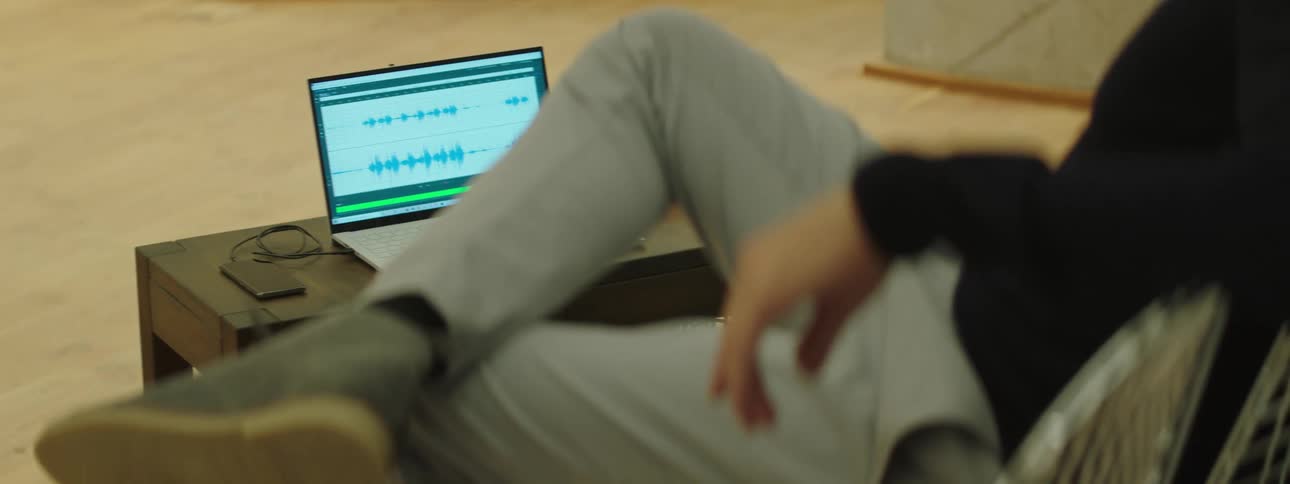 A person sitting on a chair looking at a laptop over a small coffee table