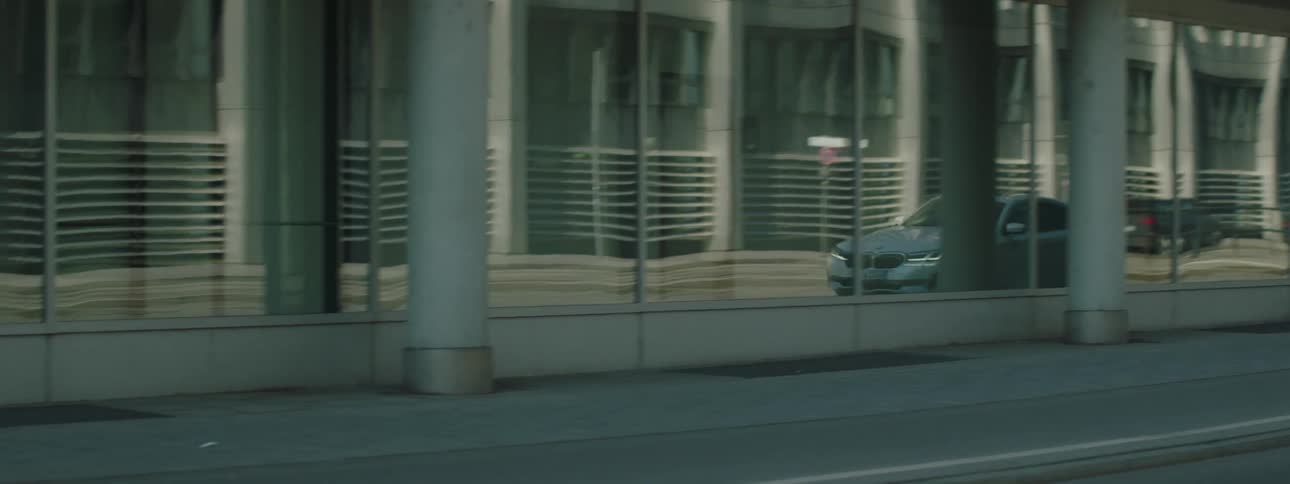 A car reflecting on the glass facade of a building in the city