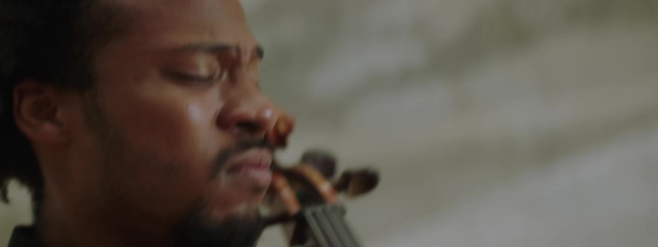 A man musician is making various expressions while playing a string instrument
