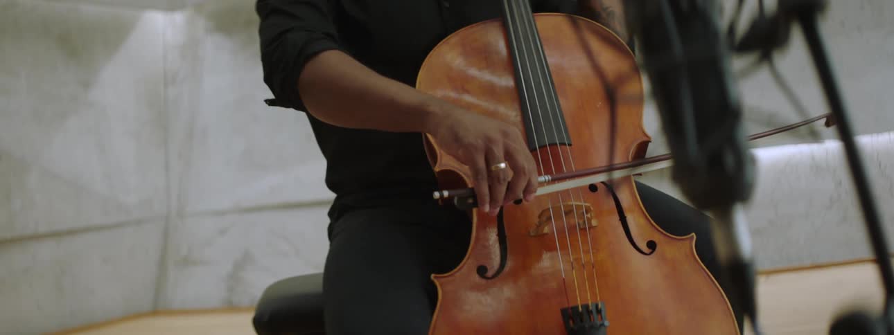An inspired musician playin the cello in front of a microphone